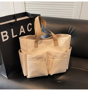 Detail of canvas tote bag with dual front zipper pockets and side compartments