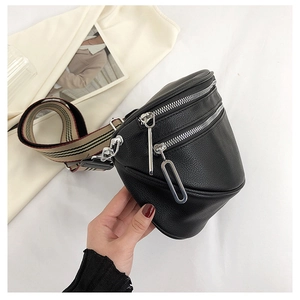 Detail of black pebbled leather crossbody bag with silver zippers and striped strap
