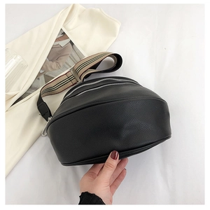Close-up of black pebble leather crossbody bag with three silver zippers and striped strap