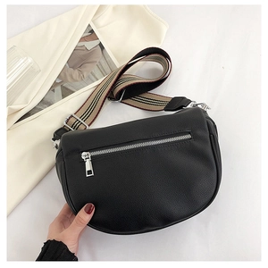 Close-up of black quilted leather crossbody bag with a striped woven wide shoulder strap
