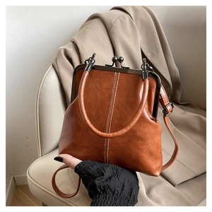 Detail of a vintage brown shell bag with metal frame closure and decorative stitching