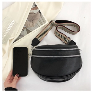 Detailed view of black pebbled leather crossbody bag with striped strap on white fabric