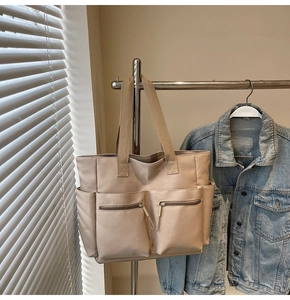 Detail of khaki canvas tote bag featuring front zipper pockets and spacious interior