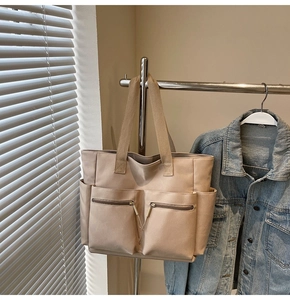 Detail showing high-capacity beige canvas tote bag with dual front zipper pockets