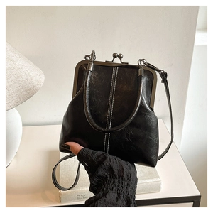 Detail of vintage black kiss-lock bag with retro metal frame and white decorative stitching