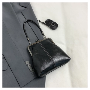 Detail of a vintage black leather doctor bag with metal clasp and detachable strap