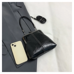 Black vintage leather doctor bag with metal handle beside a phone for scale