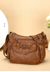 Detailed close-up of brown faux leather shoulder bag with multiple zippers and woven texture
