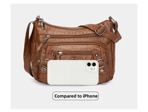 Detail view of deep brown PU leather crossbody bag with zipper pockets next to an iPhone