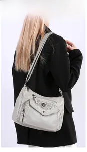 Close-up of soft grey faux leather shoulder bag with hand-woven detail and metallic logo