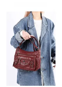 Detail of wine red PU leather shoulder bag with multi-zipper pockets and bronze hardware