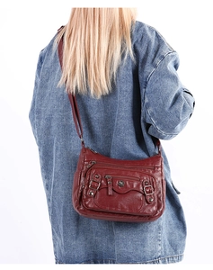 Macro detail of the wine red PU leather shoulder bag with multiple zippers and metal logo