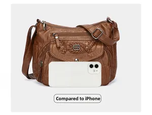 Brown leather crossbody bag detail with multiple zippers and iPhone size reference