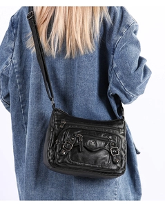 Detail view of black PU leather shoulder bag with multi-zipper pockets on blue jacket