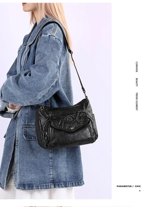 Detail of black cowhide leather shoulder bag with vintage metal buckle and woven trim