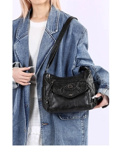 Detail of black multi-pocket crossbody bag with stitching and silver metal buckle hardware