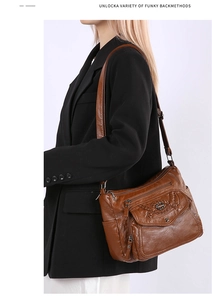 Detail of soft brown faux leather shoulder bag with multiple zippers and woven texture