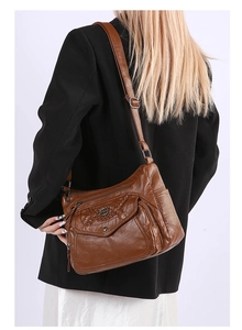 Brown soft leather crossbody bag with woven detail worn by a model in a side view