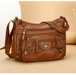 Detail of brown PU leather shoulder bag featuring multiple zippers and metallic M buckle