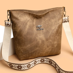 Détail d'un sac cabas vintage marron avec bandoulière ethnique large et logo métallique