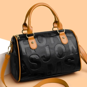 Detail of Boston bag with black lychee texture, brown leather trim and golden hardware