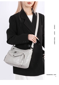 Close-up of light grey soft cowhide crossbody bag showing multiple pockets and metal logo