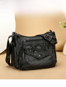 Detail of black soft leather crossbody bag with multiple zip pockets and metal logo