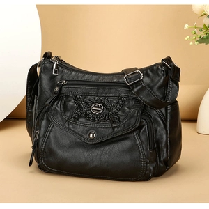 Detail of black faux leather shoulder bag with multi-zipper pockets and metal buckle