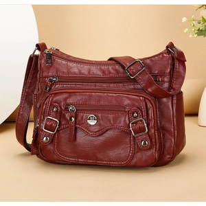Detail of burgundy soft PU leather crossbody bag with silver zippers and multi-pocket design