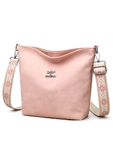Détail d'un sac bandoulière en toile rose avec sangle tissée à motifs et boucle argentée