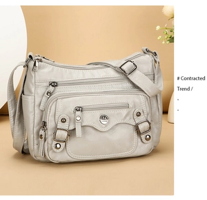 Close-up of soft PU leather shoulder bag with functional zippers and metallic logo detail