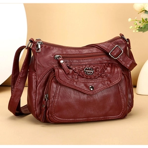 Close-up of soft burgundy leather crossbody bag with multiple zippers and woven detail