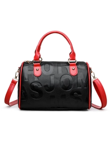 Close-up of black textured leather bag featuring red handles and gold-tone metal hardware
