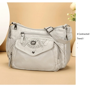 Close-up of light gray multi-pocket soft leather shoulder bag with zipper details