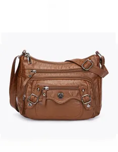 Detail of brown PU leather shoulder bag with multiple zippers and adjustable strap