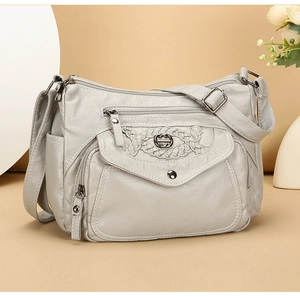 Detail showing soft gray leather handbag texture with zip pockets and woven decorative seams