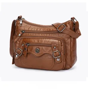 Detail view of brown PU leather shoulder bag with multiple zippers and silver hardware