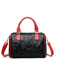 Detail of Boston bag featuring premium black lychee leather with red handles and embossing