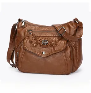 Detail of a brown multi-pocket crossbody bag featuring woven ring and silver zippers
