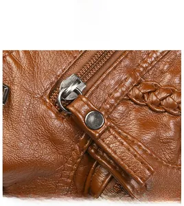 Detail of smooth silver zipper and woven leather strap on a brown textured crossbody bag