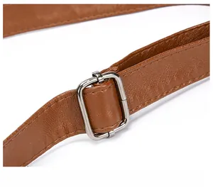 Detail of adjustable silver metal buckle on brown PU leather strap for shoulder bag