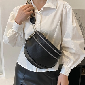 Black crescent crossbody bag with lychee texture and striped webbing strap worn by model