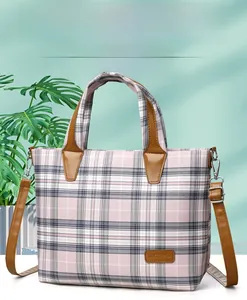 Detail of pink plaid tote bag with brown leather handles and brand nameplate detail
