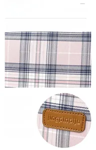 Close-up of pink and blue plaid canvas fabric with a brown faux leather logo patch detail