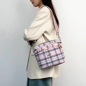 Close-up of pink plaid crossbody bag with metal kangaroo logo and geometric strap