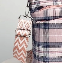 Detail of pink plaid bag showing geometric woven strap and silver metal buckle