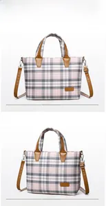 Macro detail of plaid tote bag featuring brown leather straps and branded logo patch