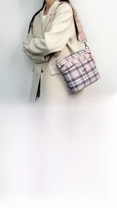 Detail of pink plaid shoulder bag with multi-zipper pockets and wide woven strap