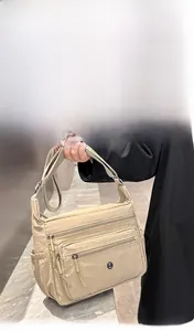 Detailed view of beige nylon crossbody bag with multi-zipper large capacity compartments