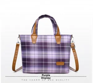 Detail view of purple plaid tote bag with brown leather handles and adjustable shoulder strap
